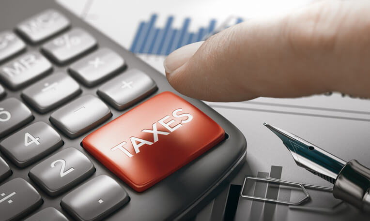 Finger pushing large button on calculator that says taxes Finger pushing large button on calculator that says taxes