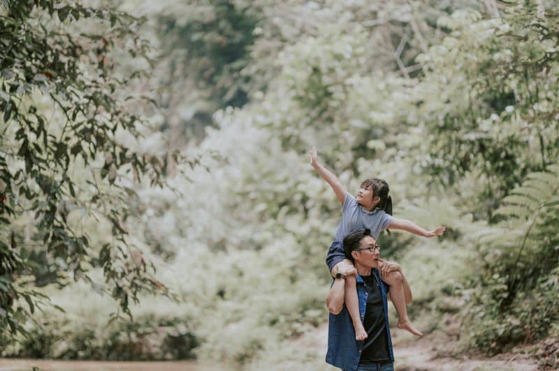 a father carrying his daughter in the woods on shoulder a father carrying his daughter in the woods on shoulder