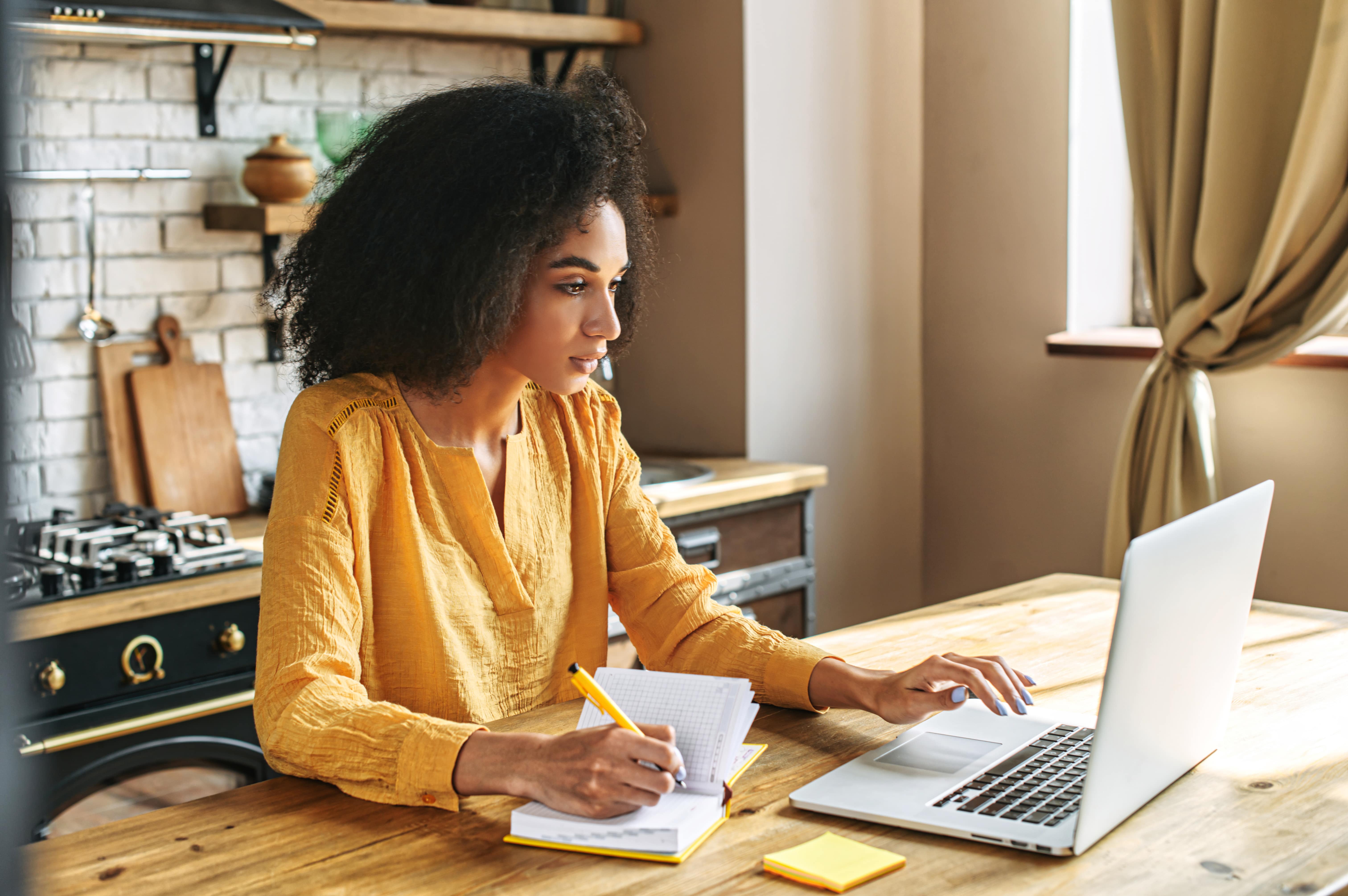 woman sits in kitchen working on laptop woman sits in kitchen working on laptop