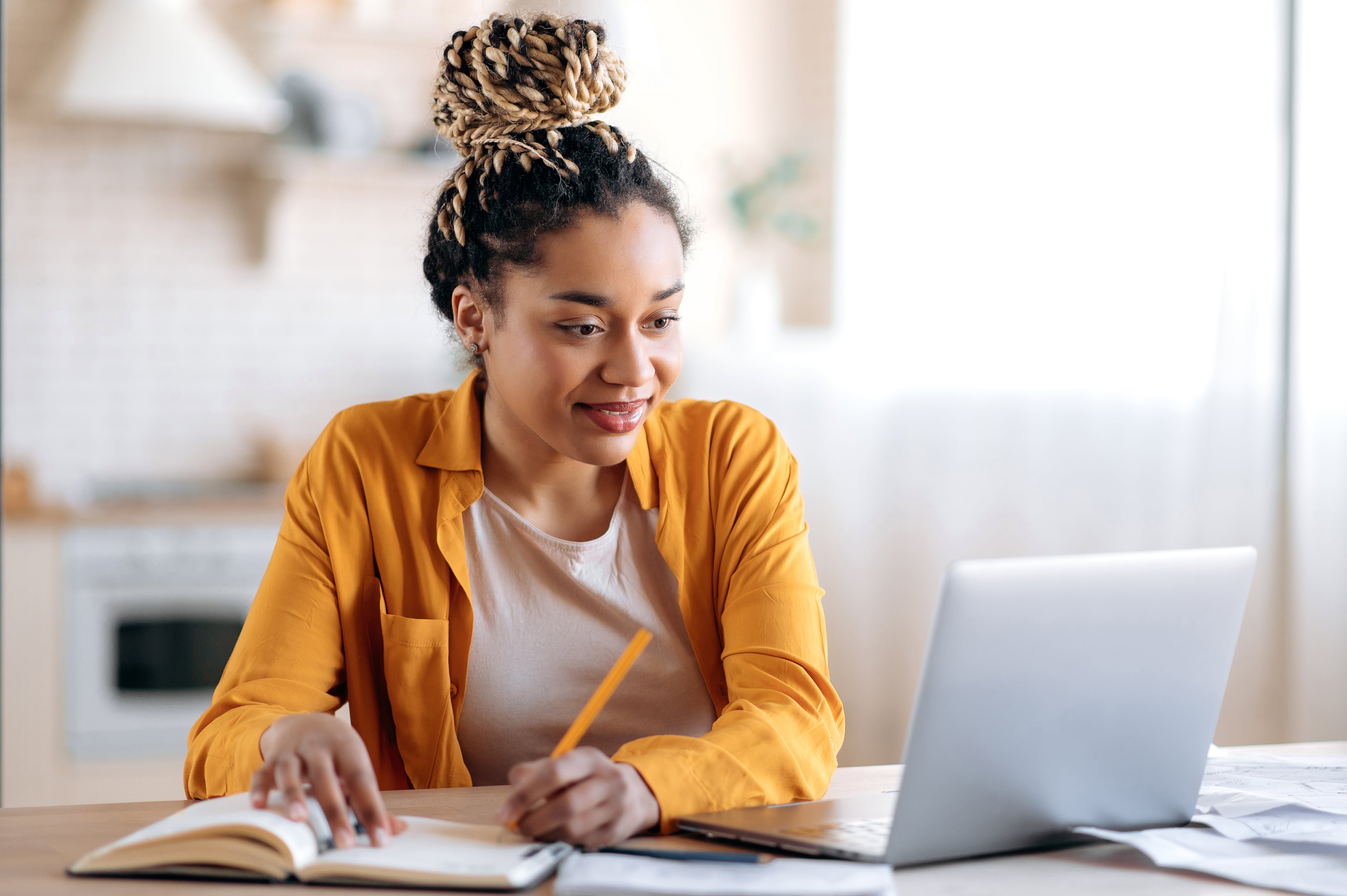 professional woman in yellow cardigan sits at desk professional woman in yellow cardigan sits at desk