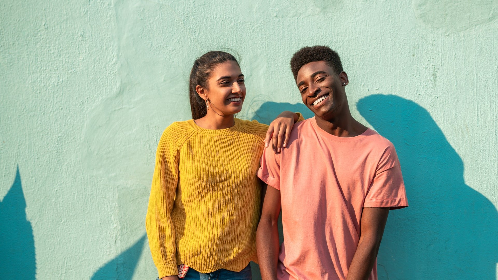 Two allied professionals in front of a teal wall