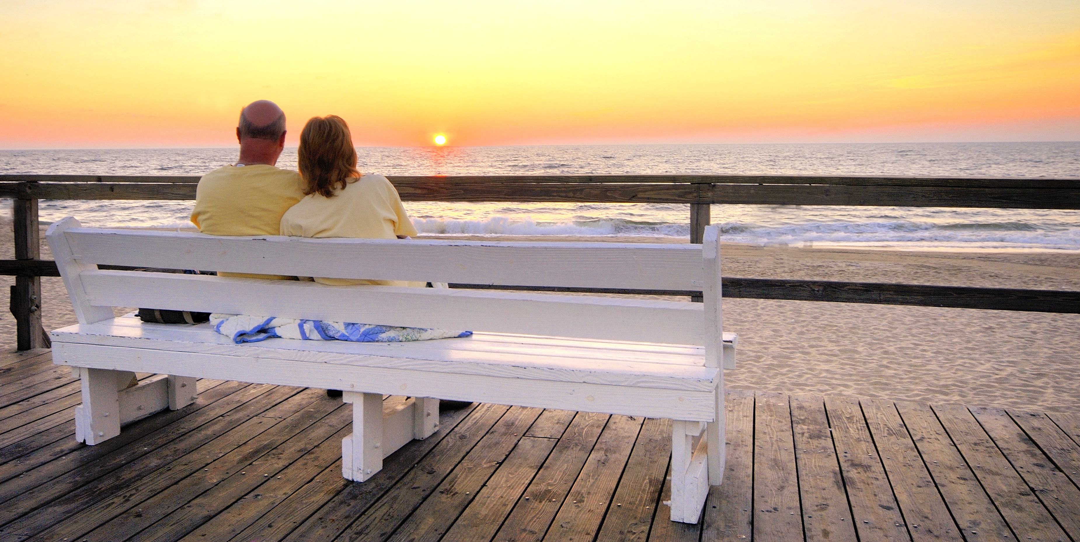 couple on bench watch sunset over beach in delaware couple on bench watch sunset over beach in delaware