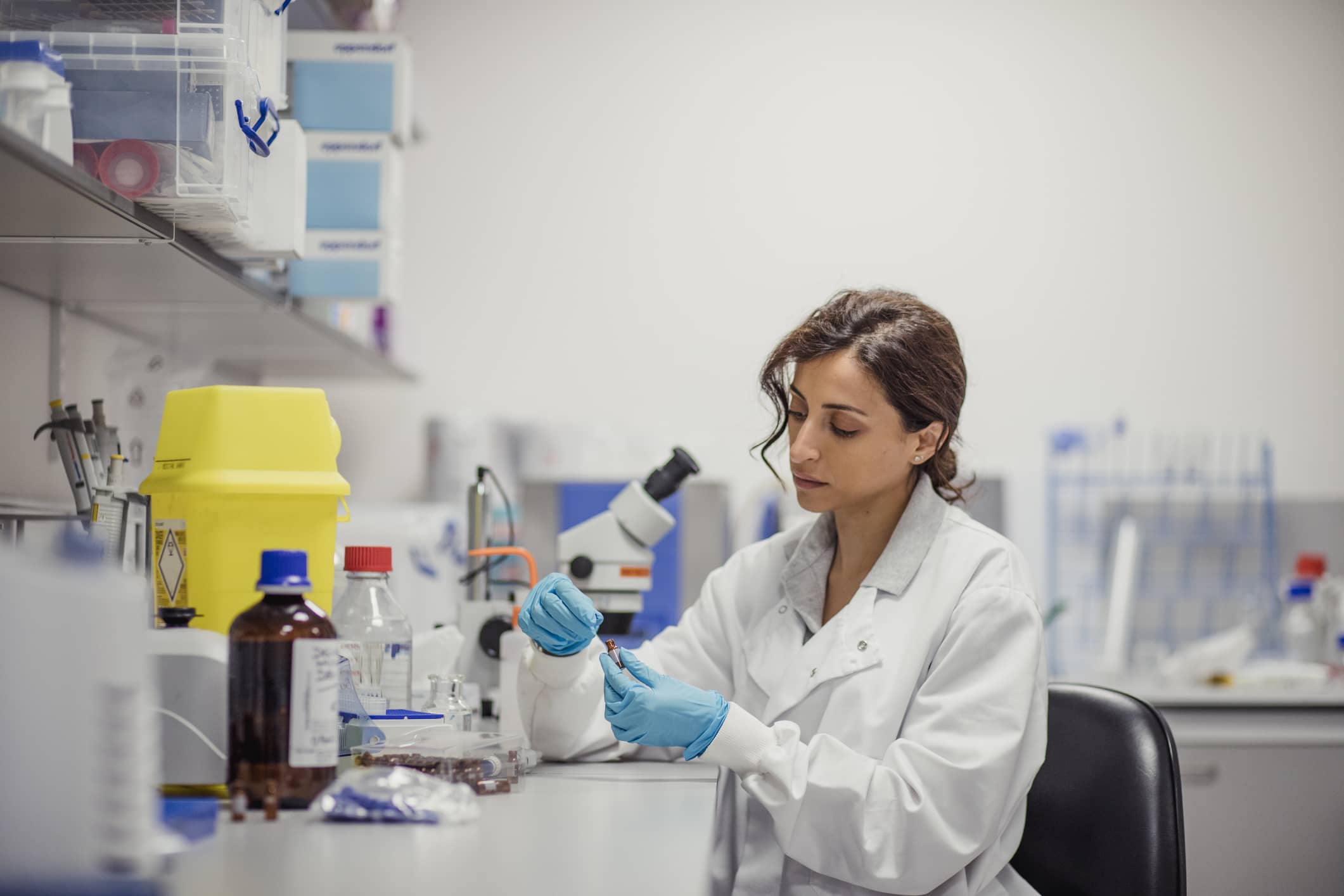 Microbiologist examines vial in lab